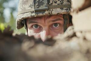 A soldier peeks through a barricade during military training exercise in a forested area in the afternoon light photo
