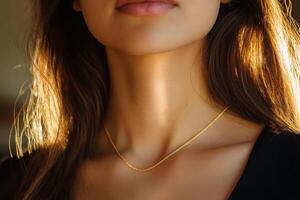 A close-up of a woman's neck illuminated by sunlight, showcasing a delicate gold necklace in a warm, cozy setting photo