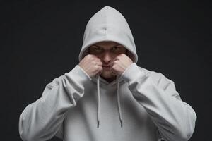 A young man wearing a gray hoodie prepares to fight in a dramatic indoor setting with a dark background and focused expression photo