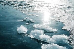 Shimmering sunlight on frozen lake with glacial ice chunks and winter reflections photo