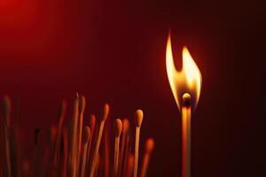 Lit matchstick among unlit matches on dark background igniting concept photo