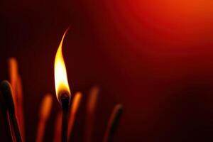 Burning matchstick with glowing flame against a dark red background concept photo