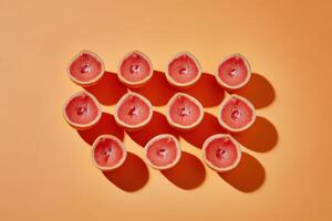 Grapefruit halves arranged in grid pattern on bright orange background photo