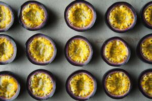 Fresh halved passion fruits in rows displaying vibrant yellow interior and texture photo