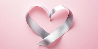 Silver ribbon shaped as heart on light pink background for symbolic design photo