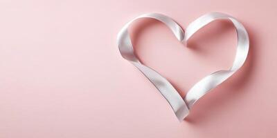 White ribbon shaped as heart on pink background symbolizing love and romance photo