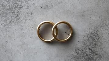 Close-up of two interlocking gold wedding rings on a textured gray background photo