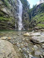 a waterfall in the mountains with rocks and water photo