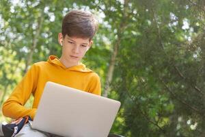Young boy using laptop. Holding and using a laptop for networking on a sunny spring day, outdoors.Copy space photo