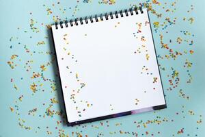 Mock up of empty sketchbook on bright vibrant background with colorful confetti. Copy space. photo