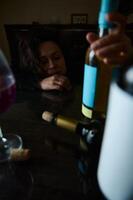 Sad woman with wine bottles on table reflecting a troubled moment photo