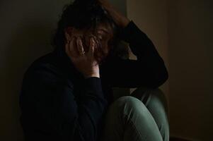 Dramatic portrayal of emotional distress in low-light introspective setting photo