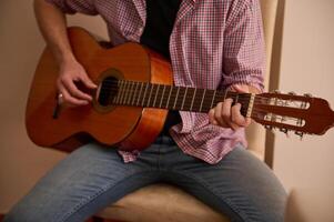 Man playing a classical guitar while sitting indoors relaxedly photo