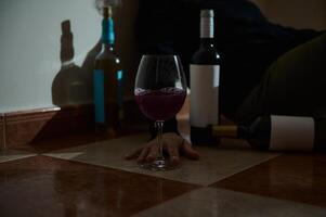 Red wine glass and empty bottles on a tiled floor photo