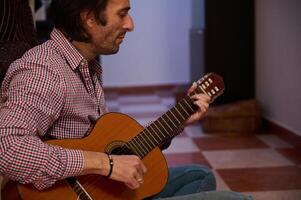 Man playing classical guitar indoors creating a relaxing and musical ambiance photo