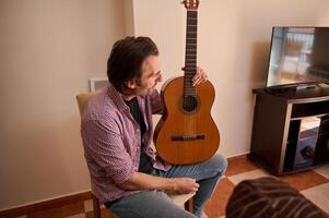 Man Holding a Classical Guitar While Sitting Indoors photo