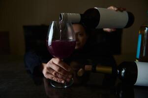 Wine being poured into a glass with a person in the background photo