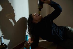Person drinking from a bottle in a dimly lit setting with shadows photo