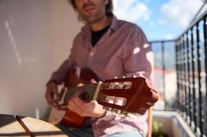 Man playing guitar on a balcony with a relaxed atmosphere photo