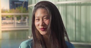 Portrait of a beautiful asian woman smiling and looking at camera outdoors in the student campus. video