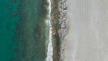 aerial drone shot of the ocean showcasing a peaceful beach alongside the clear blue sea, The tranquil waters and sandy shore create a sense of serenity and escape. video