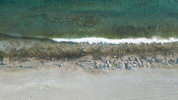 A stunning still aerial view showcasing a peaceful beach alongside the clear blue sea, The tranquil waters and sandy shore create a sense of serenity and escape. video