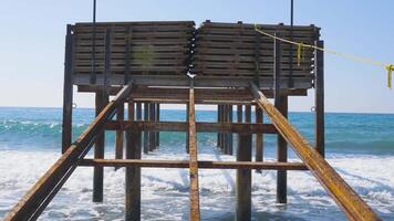 Clear Turquoise Sea Water Waves Crashing Into Beach Shore And Wooden Boardwalk on a sunny day during summer. Alanya beach Turkey with beautiful sky and clear water video