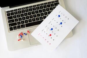 laptop with calendar and pin on the table photo