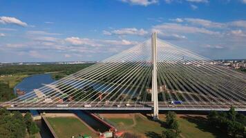 Cable stayed bridge over river surrounded by lush green forest. Redzinski bridge over Odra river with cars driving on highway in Wroclaw, Poland video