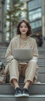young asian woman sitting on stairs with laptop and bag in city photo