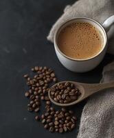 A cup of coffee and some brown coffee beans in the background photo