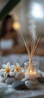 reed diffuser, candles, and rocks on the table, with frangipani flowers beside them photo