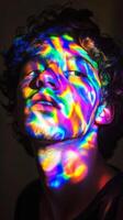 Portrait of a person with vivid rainbow light patterns on face, dark background. expressive art and photography concept photo