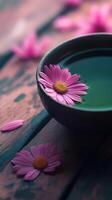 Pink daisy floating in a ceramic bowl of water on rustic wooden surface, calm and tranquil composition. Spa and relaxation concept photo
