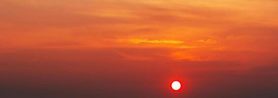 Panorama with an orange sunset and sun in a cloudy sky with clouds. Background with sky at sunrise photo