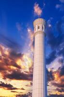 high marble white minaret of the modern new Islamic Masjid Minor Mosque in Tashkent in Uzbekistan on background of sunset sky photo