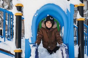 happy child boy is playing on a playground on a slide outside in winter photo