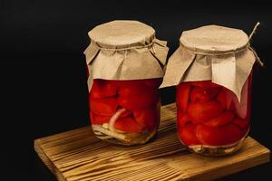 Homemade canned pickled cucumbers, tomatoes, and sweet peppers on wood photo