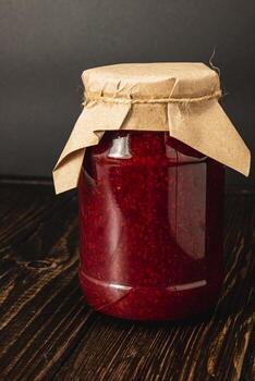 Homemade raspberry jam in a large jar with a rustic lid photo