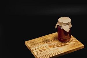 Homemade jam jar with sweet cherries and raspberries placed on wooden board photo