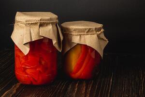 Homemade canned food featuring vibrant pickled peppers and tomatoes photo
