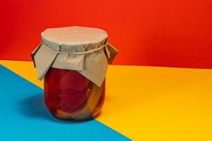 Homemade canned food featuring pickled vegetables and lard on colorful backdrop photo