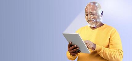 A man with a thoughtful expression interacts with a tablet, utilizing facial recognition technology. The setting features a clean, isolated background with ample copy space, emphasizing the activity. photo