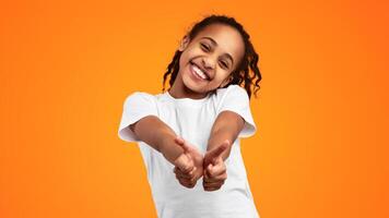 Best Choice, I Like It. Portrait of smiling black girl showing thumbs up gesture with both hands, approving or recommending something good. Teen posing isolated over yellow studio background photo