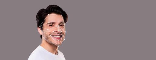 A smiling man is highlighted with facial recognition technology. Geometric lines overlay his features, demonstrating identification capabilities against a neutral background. photo