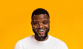 A person smiles brightly against a yellow backdrop while facial recognition technology detects facial features. The setting emphasizes the advancement in identification methods. photo