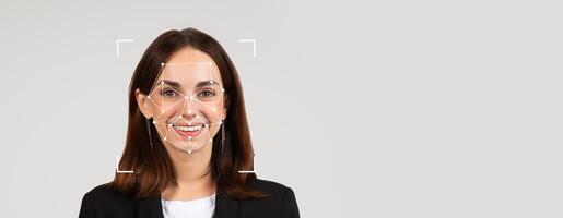 A woman smiles confidently while facial recognition technology scans her features. The neutral background enhances the focus on her expression and the technology used for identification. photo