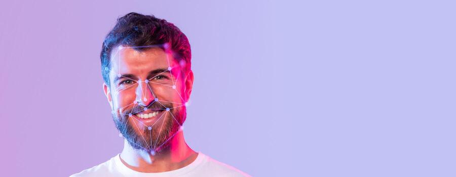 A smiling man displays facial recognition technology with vivid lighting. The background features a clean, empty space, emphasizing the facial recognition aspect and joyful expression. photo