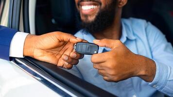 Car Renting Service. Black Male Driver Taking Keys From Manager While Sitting In Rental Auto, Unrecognizable Smiling African American Man Enjoying Vehicle Leasing, Cropped Image, Closeup photo
