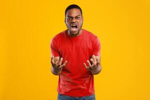 Fury. Angry African American Man Shouting Emotionally Looking At Camera Expressing Anger And Aggression Posing Over Yellow Background In Studio. Negative Emotions Concept photo